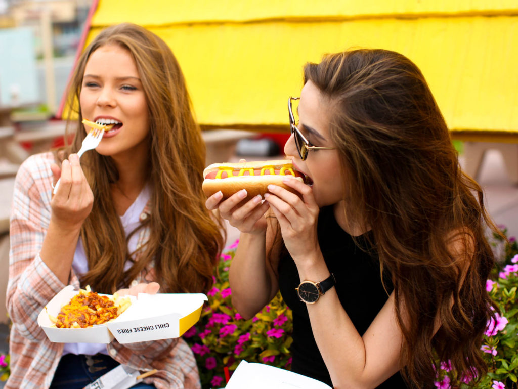 Weinerschnitzel hot dog franchise 2 girls eating a hot dog and chili fries